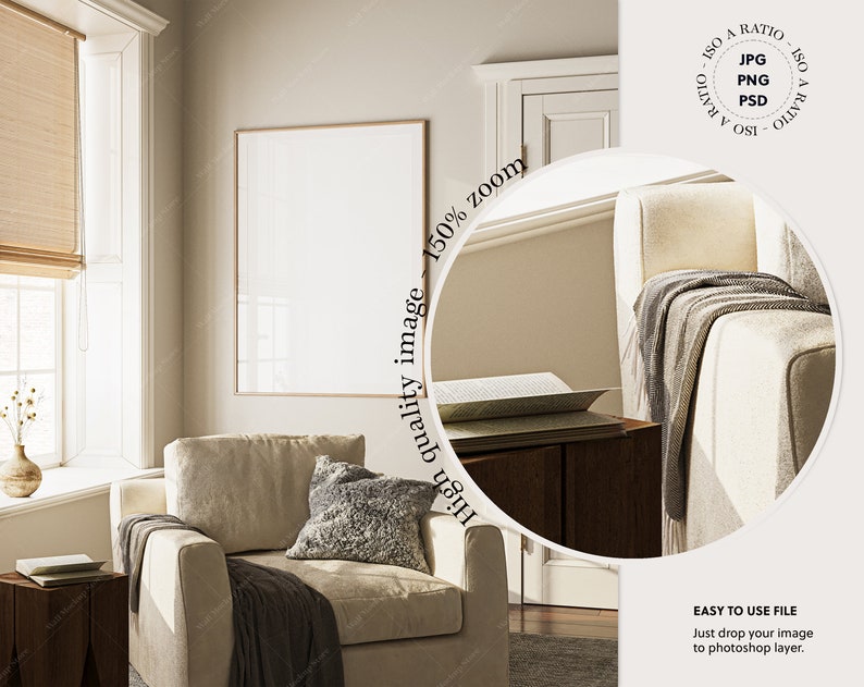 May include: A beige armchair with a gray throw blanket and a gray pillow in a living room with a large window and a framed picture on the wall.