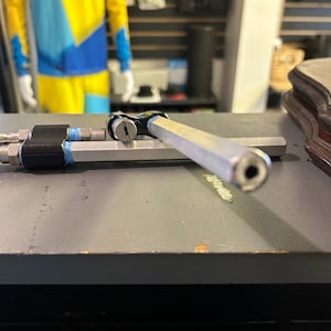 Może przedstawiać: Dwa srebrne metalowe rurki z czarnymi i niebieskimi akcentami. Rurki są połączone ze sobą i mają mały otw&oacute;r na końcu.