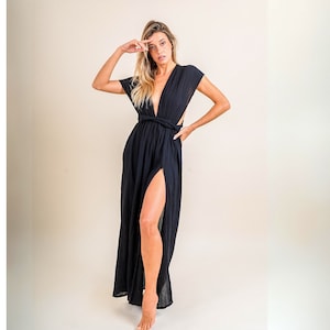 Könnte beinhalten: Eine Frau trägt ein schwarzes Maxikleid mit tiefem Ausschnitt und einem hohen Schlitz. Das Kleid hat einen Wickel-Oberteil und ist aus einem weichen, fließenden Stoff gefertigt.