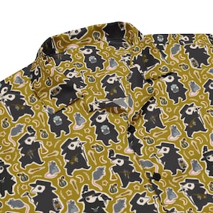 May include: A button-down shirt with a repeating pattern of plague doctor figures, rats, stars, and moons on a mustard yellow background. The plague doctor figures are black with white masks and carry various items. The shirt has a classic collar and black buttons.