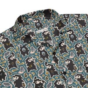 May include: Button-up shirt with a teal background and a repeating pattern of plague doctor figures, rats, stars, and other small illustrations. The shirt has a collar and black buttons. The text "becca alessi" is visible on the shirt.