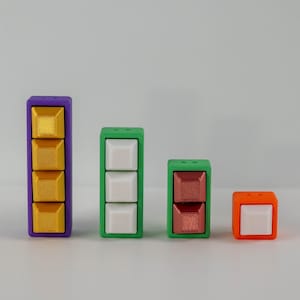 Könnte beinhalten: Vier quadratische Blöcke in verschiedenen Farben mit Knöpfen. Die Blöcke sind lila, grün, grün und orange. Die Knöpfe sind golden, weiß, kupferfarben und weiß.