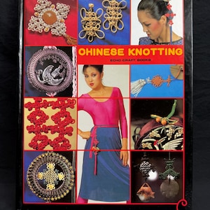 May include: A book cover titled "Chinese Knotting" with various examples of Chinese knotwork in red, gold, and white. The cover features a woman in a pink top and blue skirt, and other images of knotting.