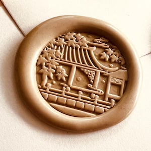 May include: A collection of colorful wax seals with a detailed Japanese-style building design. The seals are in shades of gold, purple, yellow, brown, and red. The seals are round and have a raised relief design.