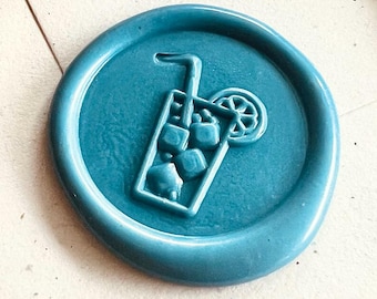 May include: A brass wax seal stamp and several colorful wax seals. The seals are in shades of blue, orange, green, and pink. Each seal features a detailed image of a refreshing iced drink with a straw and a lemon slice.