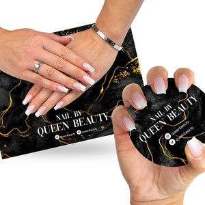 May include: Two hands with white and clear ombre nails holding a black and gold round business card with the text "Nail by Queen Beauty" and social media handles.