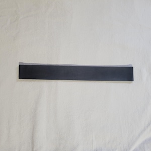 May include: A black fabric ribbon with a white edge.
