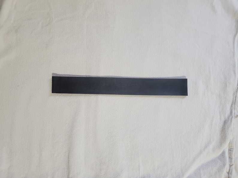 May include: A black fabric ribbon with a white edge.
