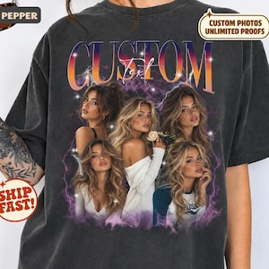 May include: A charcoal gray short-sleeve t-shirt featuring a large graphic print with the word CUSTOM in bold orange and purple gradient letters. The design includes four portraits of a woman with long blonde hair, surrounded by purple lightning and star accents.
