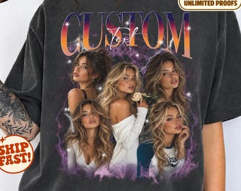 May include: A charcoal gray short-sleeve t-shirt featuring a large graphic print with the word CUSTOM in bold orange and purple gradient letters. The design includes four portraits of a woman with long blonde hair, surrounded by purple lightning and star accents.