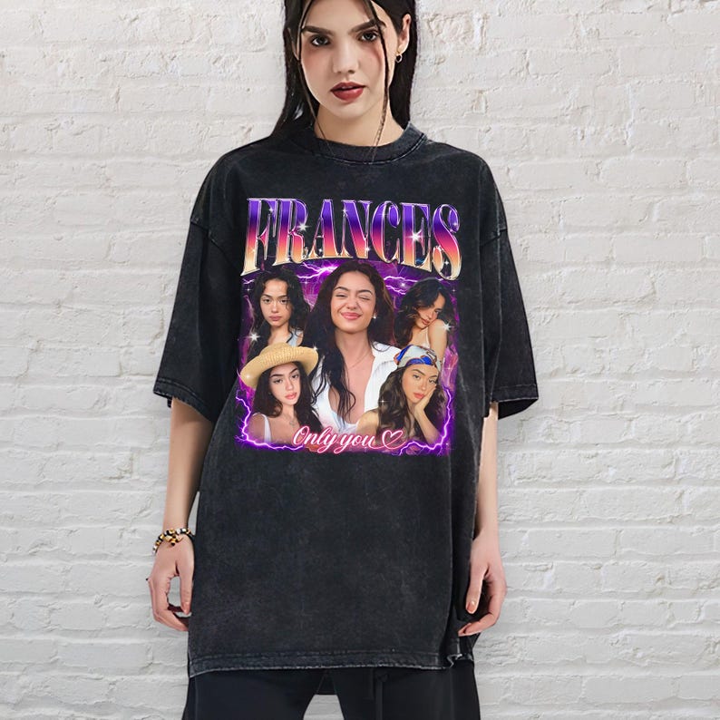 May include: Black oversized t-shirt featuring a graphic of the name "FRANCES" in a retro font, with a collage of images of a woman. The words "Only you" are below the images. The shirt has a vintage, faded look.