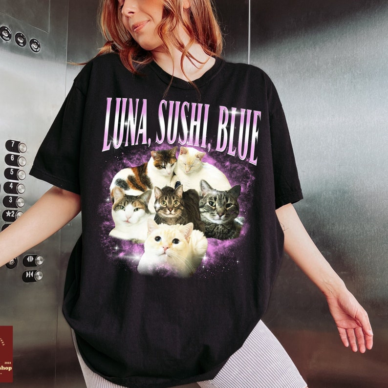 Puede incluir: Camiseta negra con un gr&aacute;fico de varios gatos y el texto "LUNA, SUSHI, BLUE" en rosa. Los gatos est&aacute;n sobre un fondo morado y blanco con tem&aacute;tica espacial.