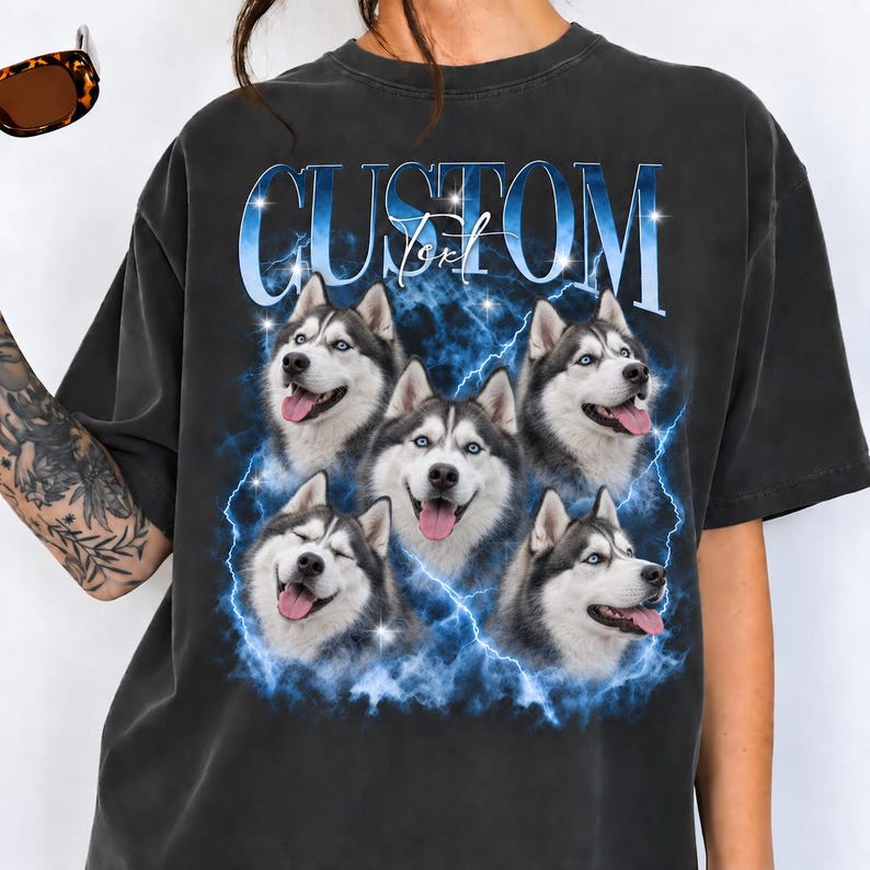 May include: A charcoal gray t-shirt featuring a graphic print of five Siberian Husky dog faces arranged in a cluster. The design includes blue lightning bolts, sparkling star accents, and the text "CUSTOM Text" in a bold blue font.