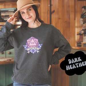 May include: Dark heather grey sweatshirt with a pink and purple 20-sided die graphic with the text "Your Roll".
