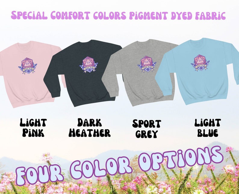 May include: Four colour options for a sweatshirt featuring a pink 20-sided die with the text "You Roll Girl" and floral accents. The sweatshirt colours are light pink, dark heather, sport grey, and light blue.