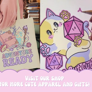 Puede incluir: Una bolsa de tela beige con un dise&ntilde;o rosa, morado y azul que presenta un libro cerrado, un mapa, una varita y un hongo. El texto "ADVENTURE READY" est&aacute; impreso en una fuente retro en la bolsa.