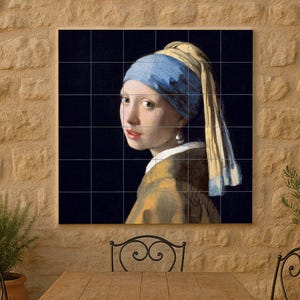 May include: A framed print of Johannes Vermeer's "Girl with a Pearl Earring" hangs on a stone wall. The painting features a young woman with a blue and yellow headscarf and a pearl earring. A wooden table and wrought iron chairs are in front.