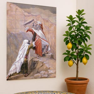 Puede incluir: Un mural decorativo de azulejos que representa una escena bíblica cuelga de una pared. Una mesa redonda con estructura de metal negro y tapa de azulejos con diseños azules y amarillos se encuentra delante. A la derecha hay un limonero en maceta.