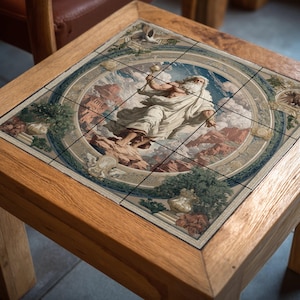 Pode incluir: Mesa de centro quadrada de madeira com um tampo de azulejo detalhado. O azulejo apresenta uma pintura clássica de uma figura em vestes brancas segurando um bastão, contra uma paisagem montanhosa. A mesa tem um acabamento em madeira natural.