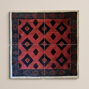 Könnte beinhalten: Quadratischer Teppich mit rotem und schwarzem Rautenmuster. Der Teppich hat einen schwarzen Rand mit geometrischen Mustern und Fransen. Der gewebte Teppich hat ein sich wiederholendes Rautenmuster.