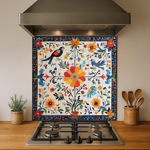 Puede incluir: Azulejo floral colorido con un diseño vibrante con pájaros, flores y follaje. El azulejo está instalado sobre una estufa de gas y debajo de una campana extractora de acero inoxidable. El diseño incluye flores naranjas, azules y amarillas.