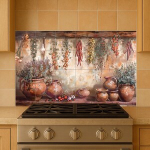 Wall-mounted ceramic artwork of traditional herbs and spices, garlic strings, and sun-dried produce over earthenware jugs.