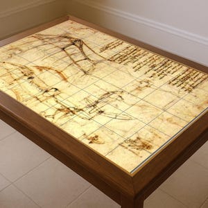 May include: Rectangular wooden coffee table with a detailed vintage map design on the tabletop. The table has a dark brown frame and legs, and the top features a grid pattern with sketches and handwritten text.