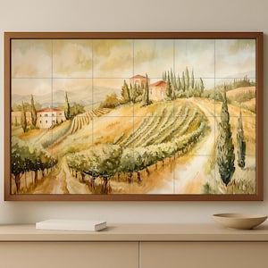 May include: A framed artwork showing a Tuscan landscape with vineyards, houses, and cypress trees. The painting uses warm tones of yellow, green, and brown, creating a sense of peace. The artwork is displayed on a light-coloured cabinet.