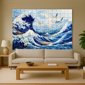 Könnte beinhalten: Ein großes Wandkunstwerk, das eine stilisierte Meereswelle in Blau- und Weißtönen darstellt, die an japanische Kunst erinnert. Das Kunstwerk zeigt eine dynamische Welle mit fliegenden Vögeln, montiert auf einem Kachelraster. Der Raum umfasst ein beiges Sofa, Holzmöbel und eine Topfpflanze.