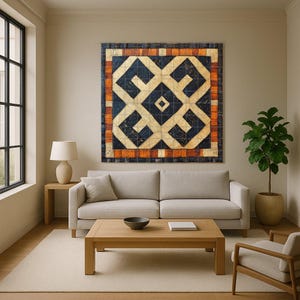 Op de afbeelding: Een groot, vierkant kunstwerk voor aan de muur met een geometrisch ontwerp in marineblauw, crème en oranje. Het kunstwerk hangt boven een lichtgrijze bank in een moderne woonkamer. De kamer heeft ook een houten salontafel, een bijzettafel met een lamp en een plant in een pot.