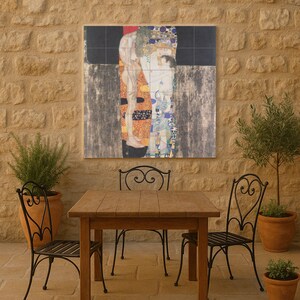 May include: A wooden table and two wrought iron chairs are set on a stone patio. A large artwork, a reproduction of Gustav Klimt's "The Kiss", hangs on the stone wall. Potted plants add greenery to the outdoor space.