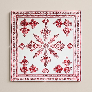 May include: Square white decorative tile with a red floral design. The tile features a central snowflake-like pattern and a border with intricate floral and geometric elements. The design is symmetrical and detailed.