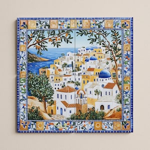 Op de afbeelding: Vierkante keramische tegel met een gedetailleerde schildering van een kustdorp met witte gebouwen, blauwe koepels en oranje daken. Het kunstwerk is omlijst door een blauw-gele bloemenrand, met een blauwe zee en lucht op de achtergrond.