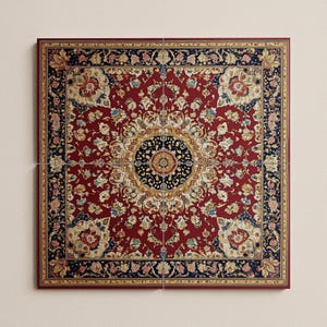 May include: A square, framed wall art piece featuring a detailed, ornate rug design. The rug has a deep red background with a central medallion and floral patterns in cream, blue, and gold. The frame is a dark, reddish-brown color.