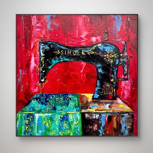 Pode incluir: Uma pintura abstrata colorida de uma máquina de costura Singer vintage em uma mesa com uma toalha de mesa estampada. O fundo é um vermelho vibrante com respingos de azul e amarelo.