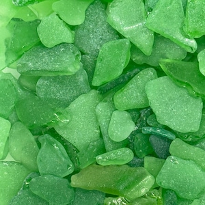 May include: A collection of smooth, green sea glass pieces. The glass is translucent and has a variety of shapes and sizes.
