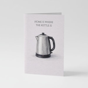 Puede incluir: Una tarjeta de felicitación con el texto "HOME IS WHERE THE KETTLE IS" sobre una ilustración de una tetera eléctrica plateada. La tetera tiene un asa y una base negras, y una luz roja está encendida.