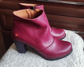 May include: A pair of burgundy leather ankle boots with a block heel and a zipper on the side. The boots have a small orange star embroidered on the side.