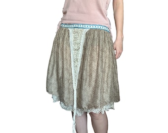 May include: A brown and white patterned skirt with a white lace trim and a blue and white patterned waistband.