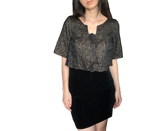 Peut inclure: Un haut en dentelle noire à manches courtes et motif doré. Le haut est court et a un col en V. Le mannequin porte une jupe en velours noir.