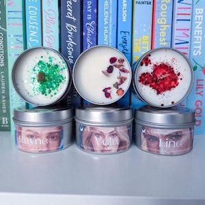 Peut inclure: Trois boîtes de bougies en argent avec de la cire et des paillettes de différentes couleurs. Les bougies sont étiquetées "Rayne", "Vela" et "Ling".