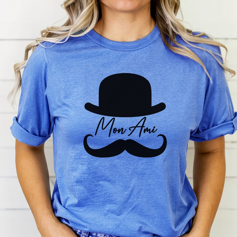 May include: A blue t-shirt with a black bowler hat, mustache, and the text "Mon Ami" printed on the front.