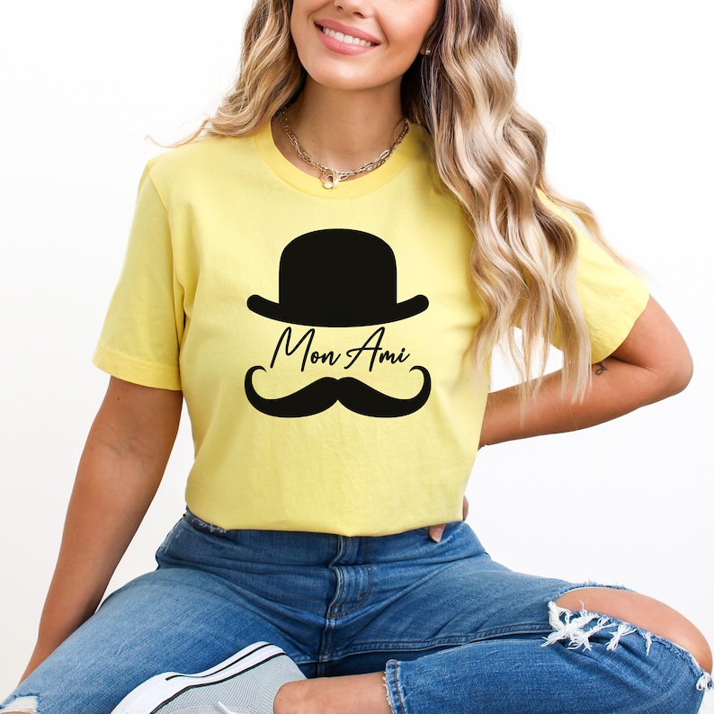 May include: A yellow t-shirt with a black bowler hat, mustache, and the text "Mon Ami" printed on the front.