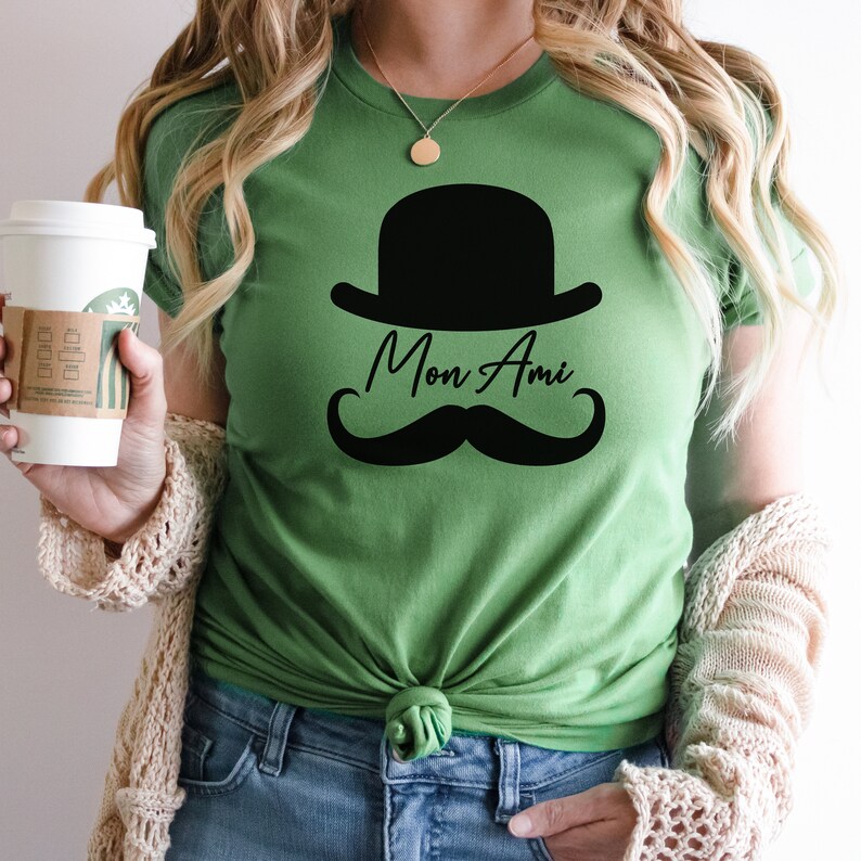 May include: A green t-shirt with a black bowler hat and mustache graphic and the text "Mon Ami".