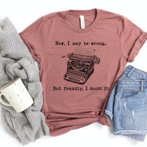 May include: A mauve t-shirt with a vintage typewriter graphic and the text "Now, I may be wrong... But frankly, I doubt it."