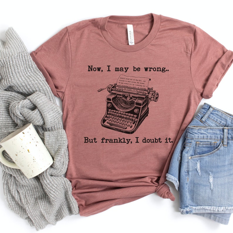 May include: A mauve t-shirt with a vintage typewriter graphic and the text "Now, I may be wrong... But frankly, I doubt it."