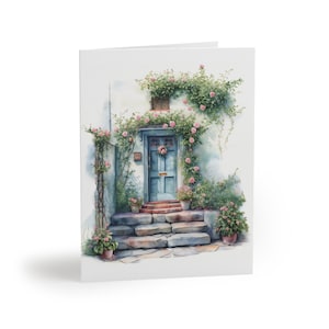 Może przedstawiać: Akwarela przedstawiająca niebieskie drzwi z wieńcem na białym domu ze schodami kamiennymi i różowymi kwiatami.