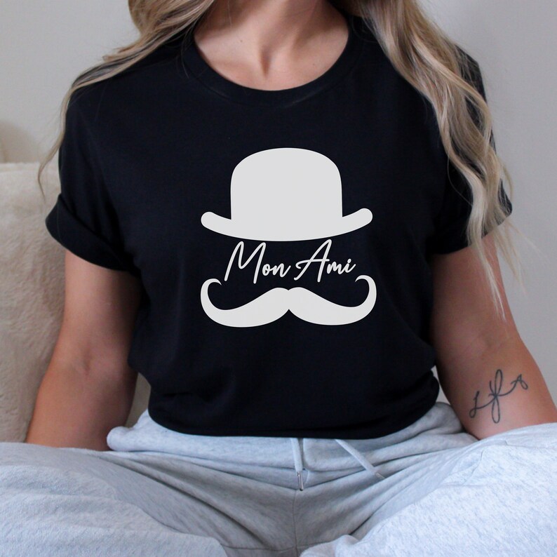 May include: Black t-shirt with a white graphic of a bowler hat, mustache, and the text "Mon Ami".