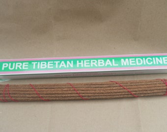 May include: A box of brown incense sticks tied with red string. The box is green with pink and white lettering that reads "PURE TIBETAN HERBAL MEDICINE".