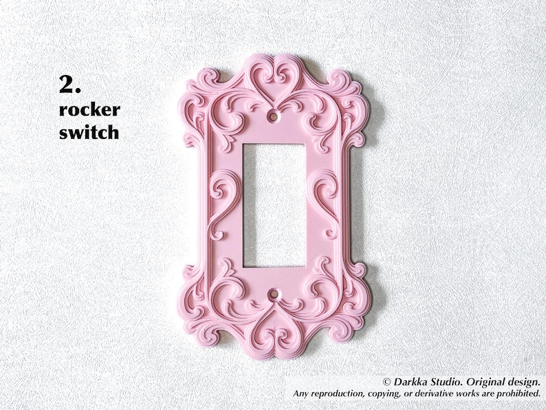 Puede incluir: Una cubierta rosa para interruptor basculante con un dise&ntilde;o ornamental de volutas. La cubierta tiene una abertura rectangular para el interruptor y est&aacute; etiquetada como "2. rocker switch".